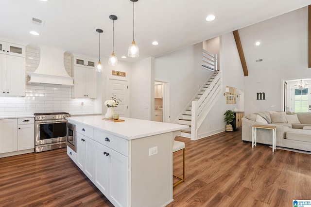 kitchen featuring white cabinetry, a center island, custom range hood, and appliances with stainless steel finishes