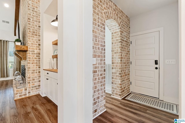 interior space with brick wall and dark hardwood / wood-style floors