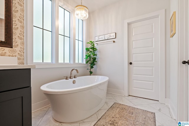 bathroom with vanity, an inviting chandelier, and a tub