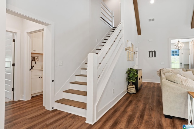 stairway with beam ceiling, a chandelier, and wood-type flooring