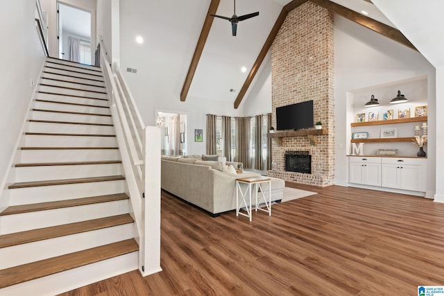 living room featuring dark hardwood / wood-style flooring, ceiling fan, high vaulted ceiling, beamed ceiling, and a fireplace