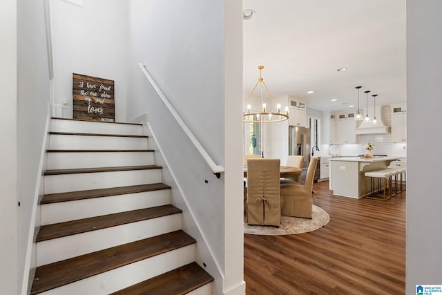 staircase featuring wood-type flooring and a chandelier