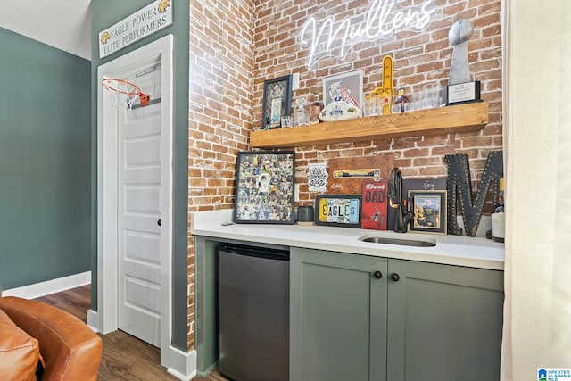 bar with sink, refrigerator, dark wood-type flooring, and brick wall