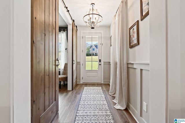 doorway with a chandelier, wood-type flooring, and a barn door