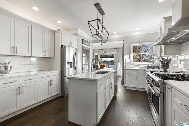 kitchen featuring white cabinetry, pendant lighting, stainless steel appliances, and wall chimney range hood