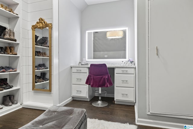 walk in closet with dark hardwood / wood-style flooring, built in desk, and vaulted ceiling