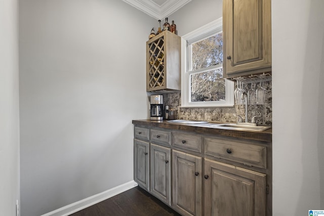 bar featuring sink, ornamental molding, backsplash, and dark wood-type flooring