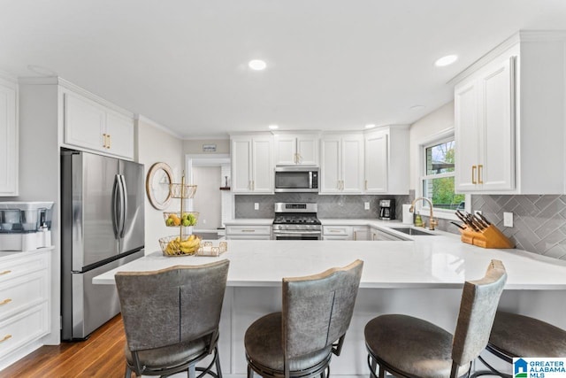 kitchen with a breakfast bar area, kitchen peninsula, white cabinets, and appliances with stainless steel finishes