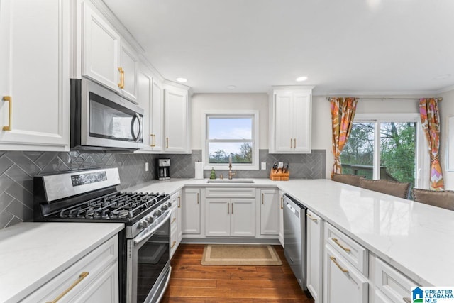 kitchen featuring white cabinets, sink, light stone countertops, and stainless steel appliances