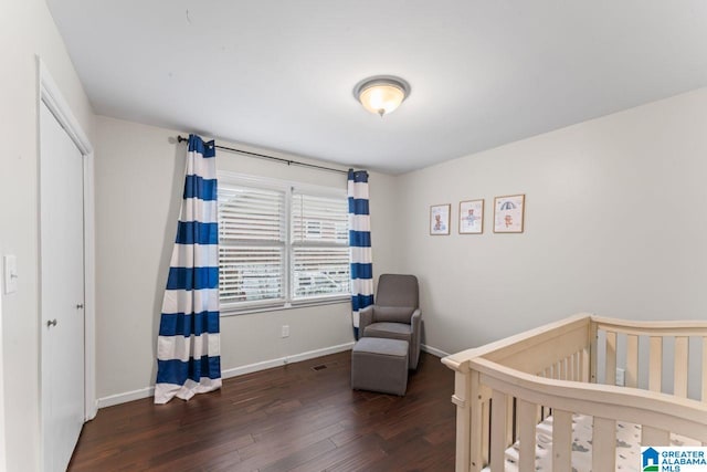 bedroom with dark hardwood / wood-style flooring and a crib