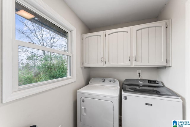 clothes washing area with cabinets and washing machine and clothes dryer