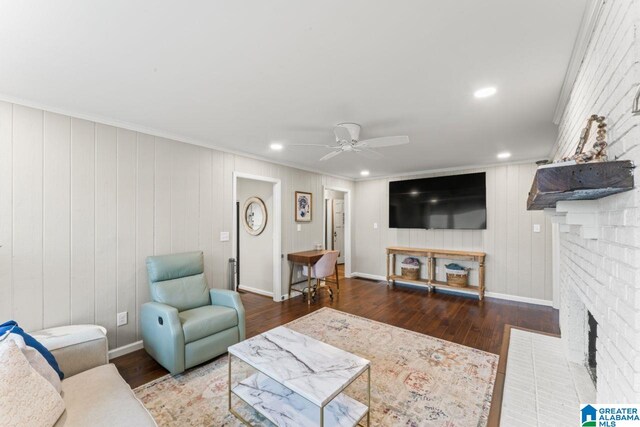 living room featuring dark hardwood / wood-style flooring, a brick fireplace, ceiling fan, and ornamental molding