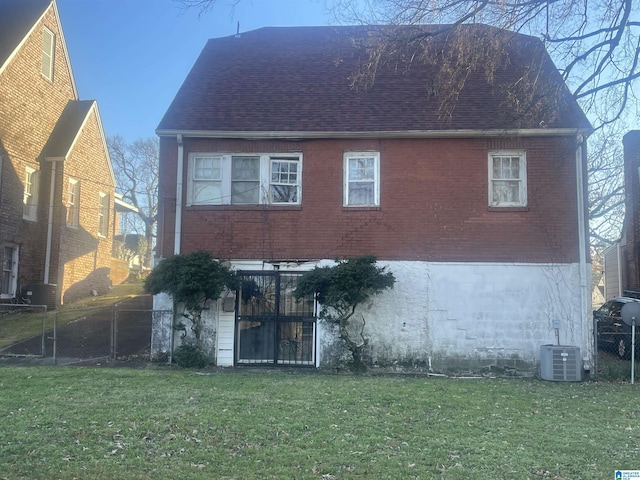 rear view of house with a lawn and cooling unit