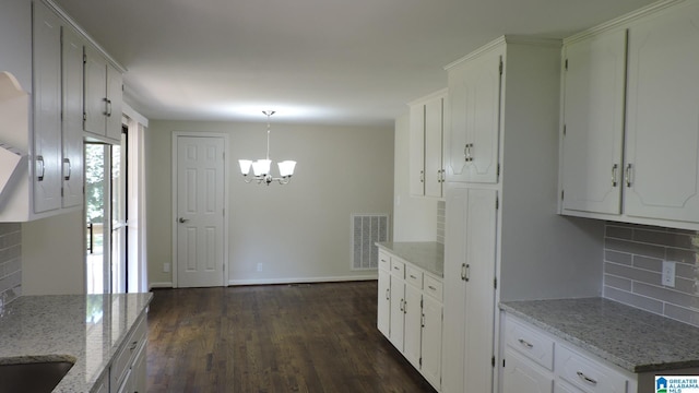 kitchen with dark hardwood / wood-style floors, light stone counters, white cabinetry, and hanging light fixtures