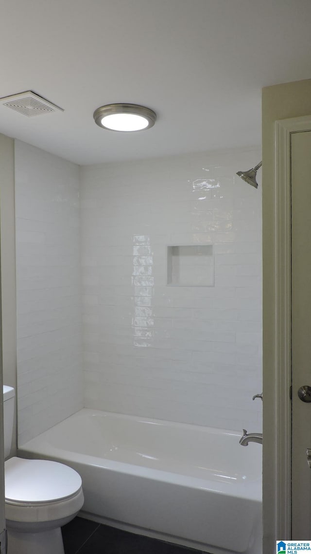 bathroom with tile patterned flooring, tiled shower / bath, and toilet