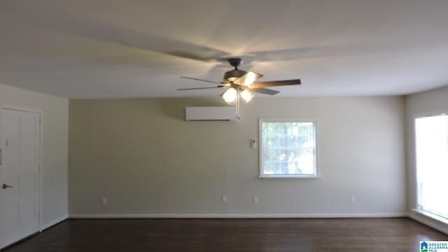 unfurnished room featuring a wall mounted AC, dark hardwood / wood-style flooring, and plenty of natural light