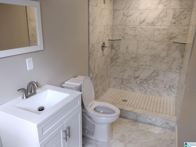 bathroom featuring a tile shower, vanity, and toilet