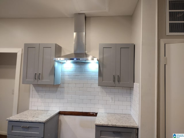 kitchen with tasteful backsplash, gray cabinets, and wall chimney range hood