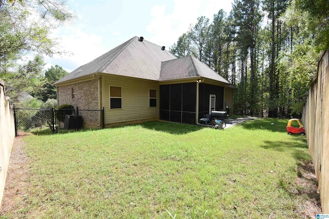 back of property with a sunroom, a yard, and central AC unit