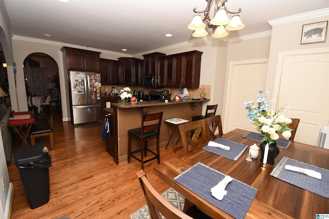 kitchen featuring hanging light fixtures, stainless steel appliances, a kitchen breakfast bar, a notable chandelier, and kitchen peninsula