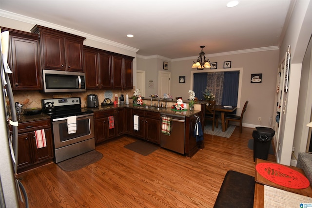 kitchen featuring backsplash, sink, appliances with stainless steel finishes, kitchen peninsula, and a chandelier