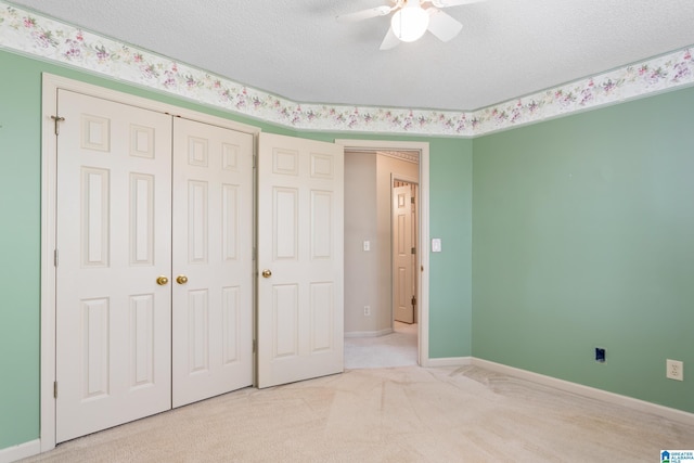 unfurnished bedroom featuring ceiling fan, a textured ceiling, light carpet, and a closet