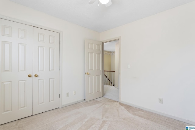 unfurnished bedroom featuring ceiling fan, light carpet, and a closet