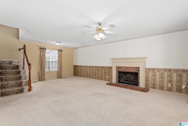 unfurnished living room featuring carpet, ceiling fan, crown molding, and a fireplace