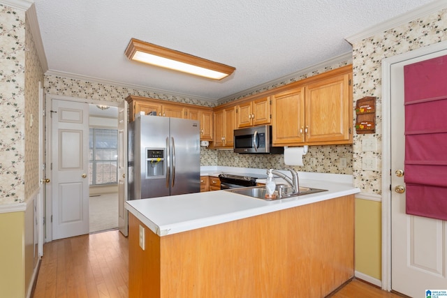 kitchen with sink, stainless steel appliances, kitchen peninsula, light hardwood / wood-style floors, and a textured ceiling