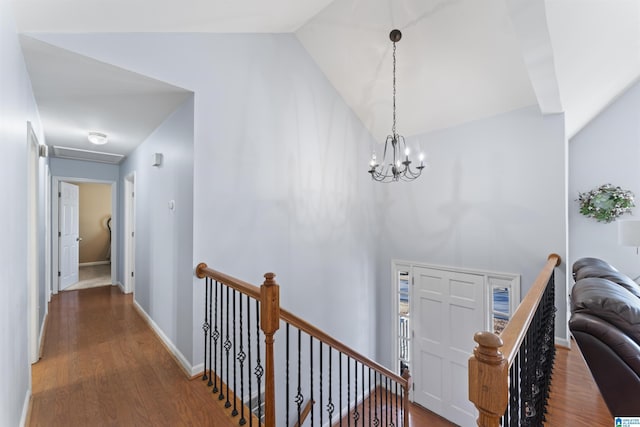 corridor featuring dark hardwood / wood-style floors, lofted ceiling, and an inviting chandelier