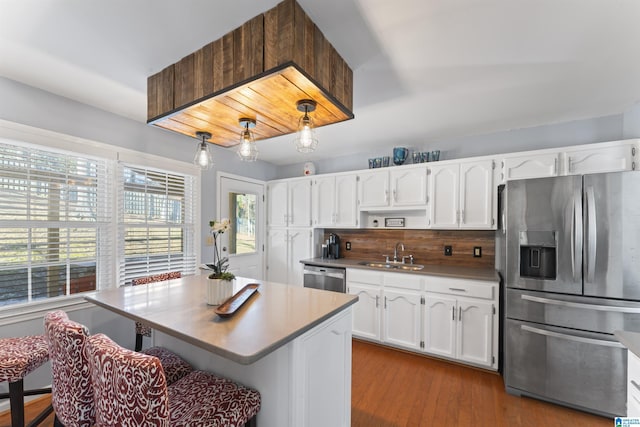 kitchen featuring decorative backsplash, stainless steel appliances, sink, white cabinets, and hanging light fixtures