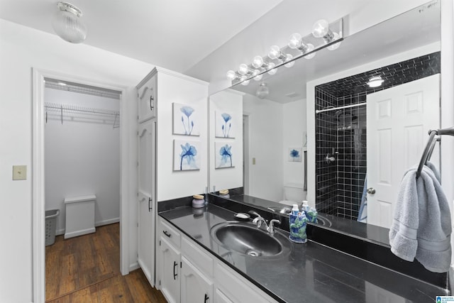 bathroom with tiled shower, hardwood / wood-style floors, and vanity