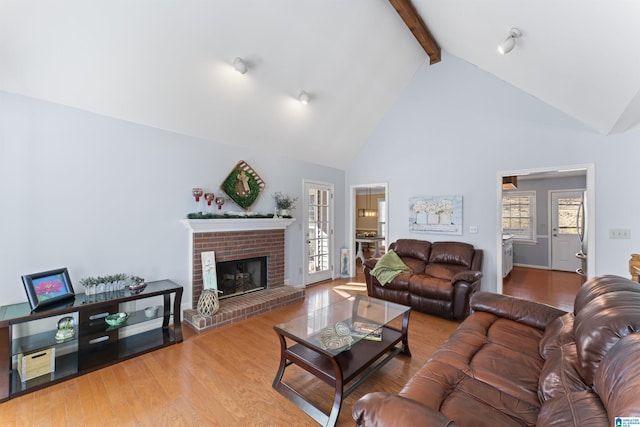 living room with a fireplace, light hardwood / wood-style floors, high vaulted ceiling, and beamed ceiling