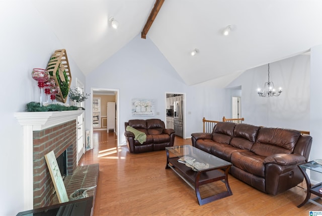 living room with high vaulted ceiling, an inviting chandelier, light wood-type flooring, a fireplace, and beamed ceiling