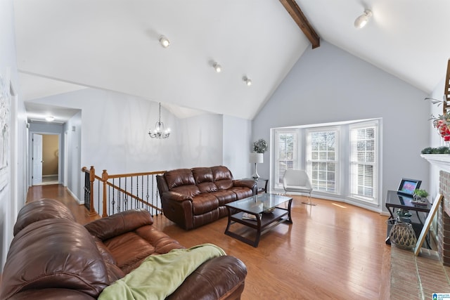 living room featuring beam ceiling, a brick fireplace, high vaulted ceiling, a chandelier, and light hardwood / wood-style floors