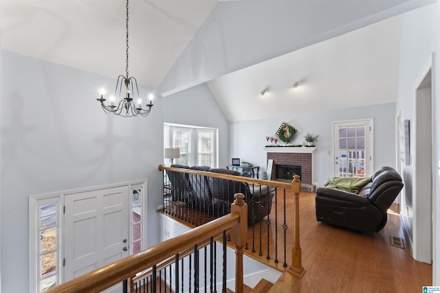 hall featuring hardwood / wood-style flooring, lofted ceiling, and an inviting chandelier