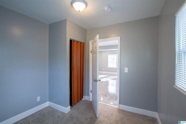 unfurnished bedroom with a closet and light colored carpet