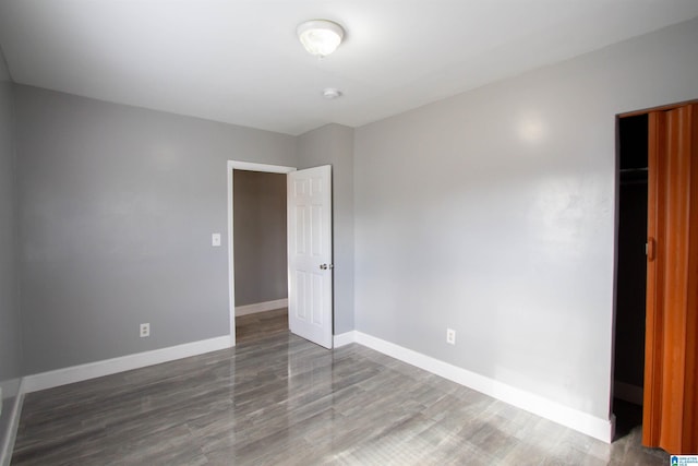 unfurnished bedroom with dark hardwood / wood-style flooring and a closet