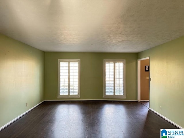 unfurnished room featuring dark wood-type flooring and a textured ceiling