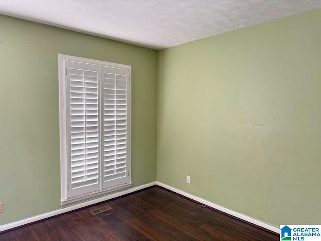 unfurnished room with a textured ceiling and dark hardwood / wood-style floors