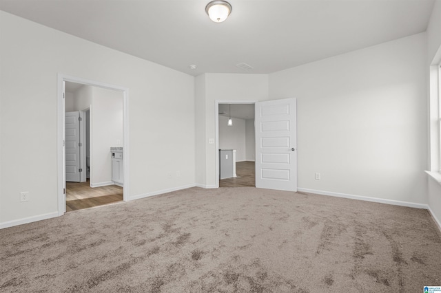 unfurnished bedroom with light carpet and connected bathroom