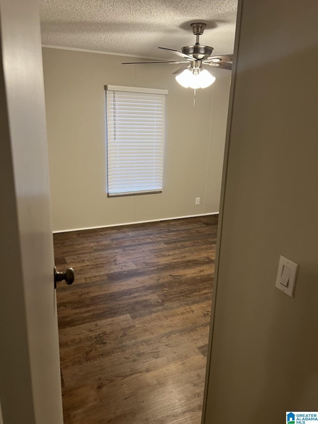 empty room featuring ceiling fan, dark hardwood / wood-style flooring, and a textured ceiling