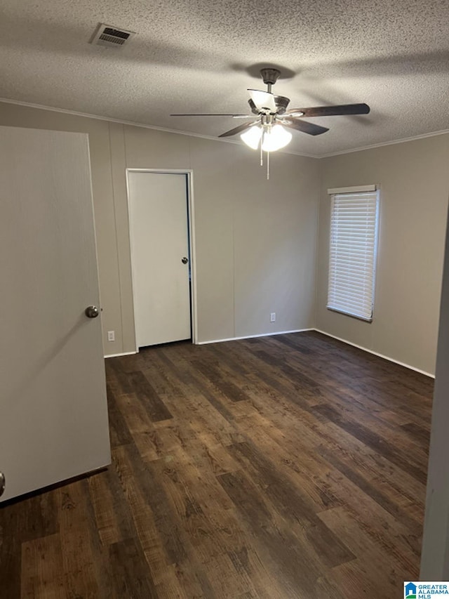 empty room featuring ceiling fan, dark hardwood / wood-style floors, a textured ceiling, and ornamental molding