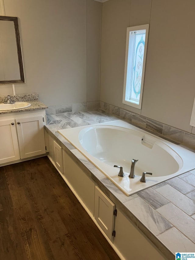 bathroom with a washtub, wood-type flooring, and vanity