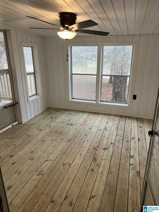 unfurnished room featuring ceiling fan, a healthy amount of sunlight, wood ceiling, and wooden walls