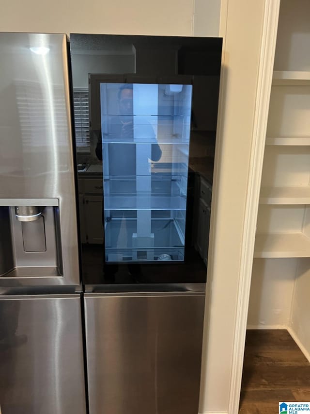 interior details featuring stainless steel fridge with ice dispenser and dark wood-type flooring