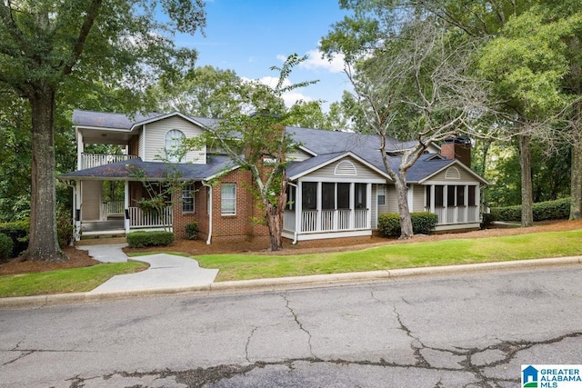 view of front of property with a front yard, a porch, and a sunroom