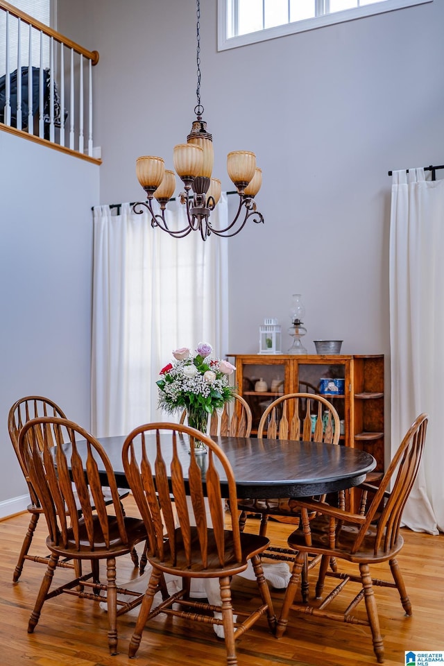 dining space featuring light wood-type flooring, a high ceiling, and a notable chandelier