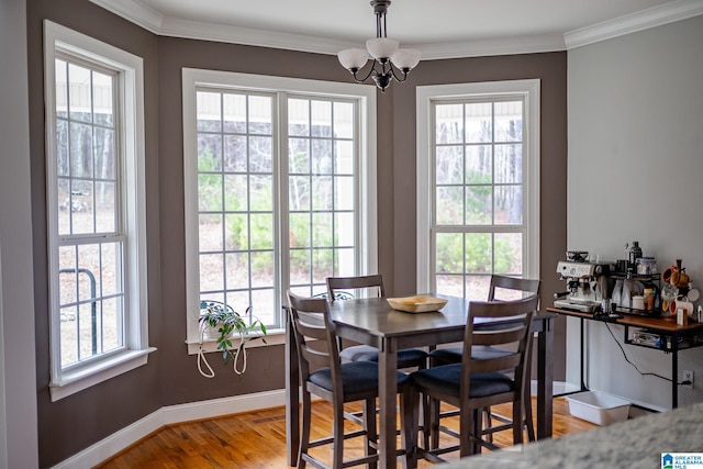 dining area with crown molding, wood-type flooring, a healthy amount of sunlight, and a notable chandelier