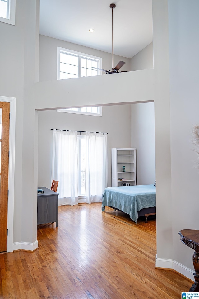 unfurnished bedroom featuring ceiling fan, a towering ceiling, and light hardwood / wood-style flooring